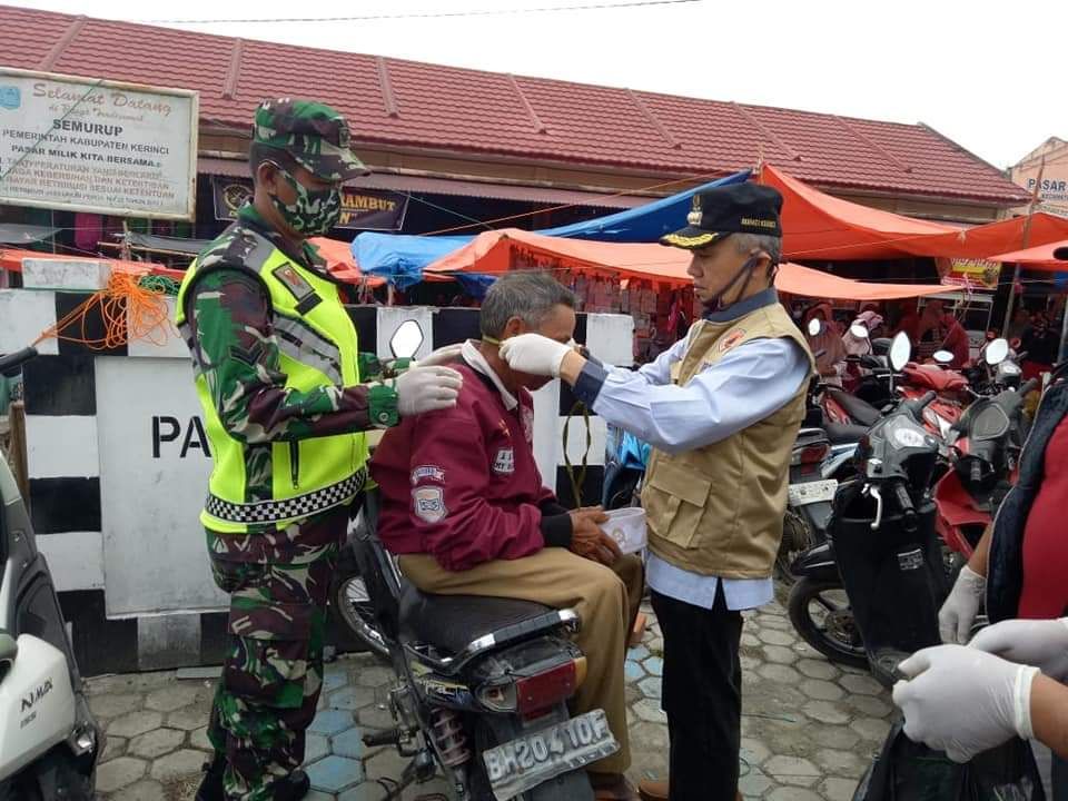 Bupati Kerinci H. Adirozal Saat memakaikan Masker kepada salah seorang warga dipasar Semurup


