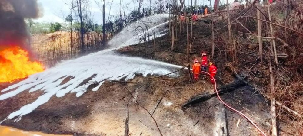 Kerusakan lingkungan yang diakibatkan oleh sumur minyak ilegal. Tampak petugas sedang memadamkan api